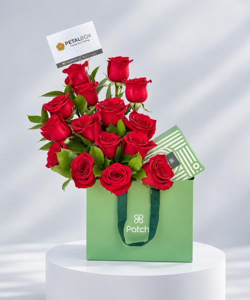 Luxury red rose arrangement featuring fresh red roses and green foliage in a premium green Patchi gift bag, perfect for romantic occasions, anniversaries and Valentine's Day flower gifting in Abu Dhabi and Dubai, UAE.