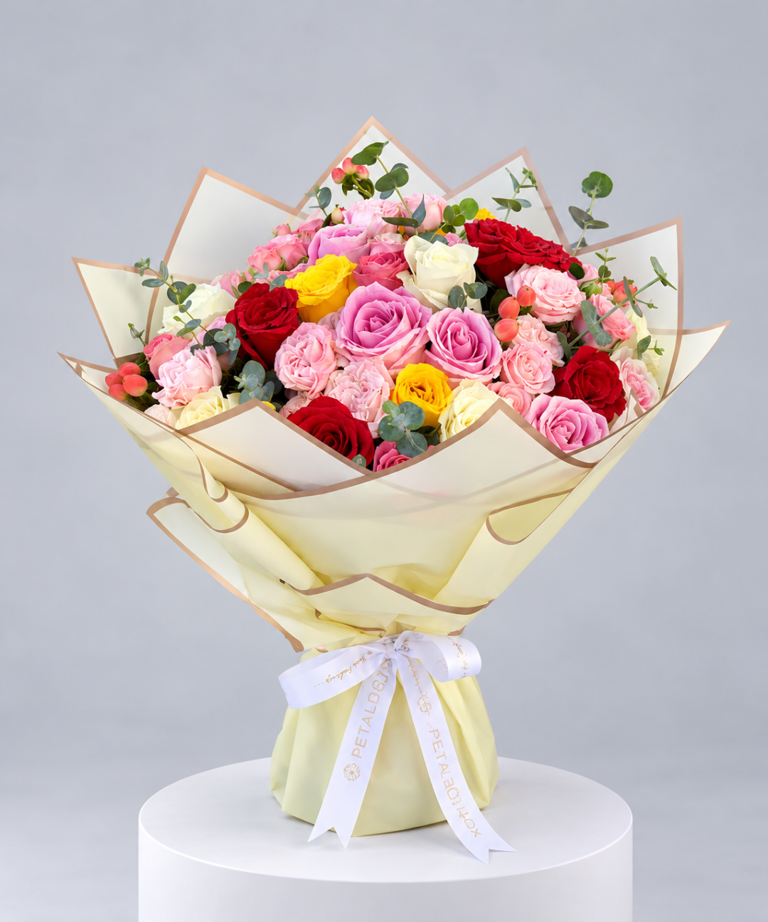 luxury mixed rose bouquet featuring pink, red, yellow and cream roses with eucalyptus foliage, wrapped in elegant ivory and sage green paper with a white Petal Box ribbon, premium flower delivery in Abu Dhabi and Dubai for birthdays, anniversaries and special occasions
