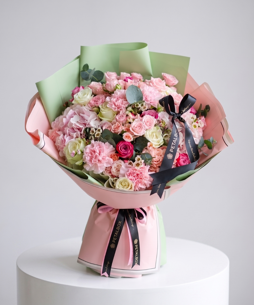 Premium pink and pastel mixed flower bouquet with roses, carnations, hydrangeas and eucalyptus, wrapped in pink and sage green paper with black Petal Box ribbons, perfect for gifting in Abu Dhabi and Dubai, UAE.