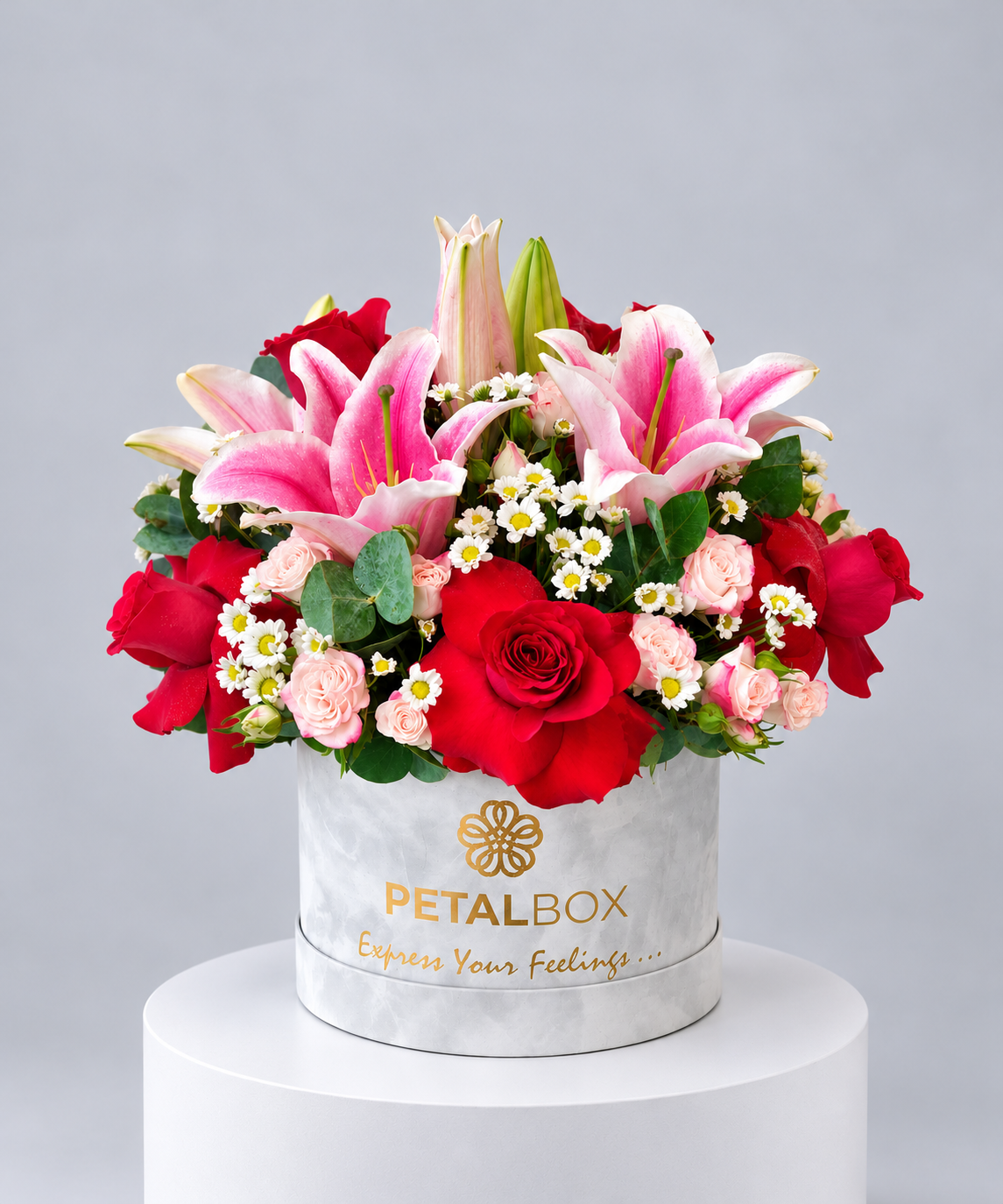 luxury flower arrangement in a white Petal Box hatbox featuring vibrant red roses, pink lilies, blush pink roses, white daisies and fresh green foliage, elegant floral gift for special occasions in Abu Dhabi and Dubai
