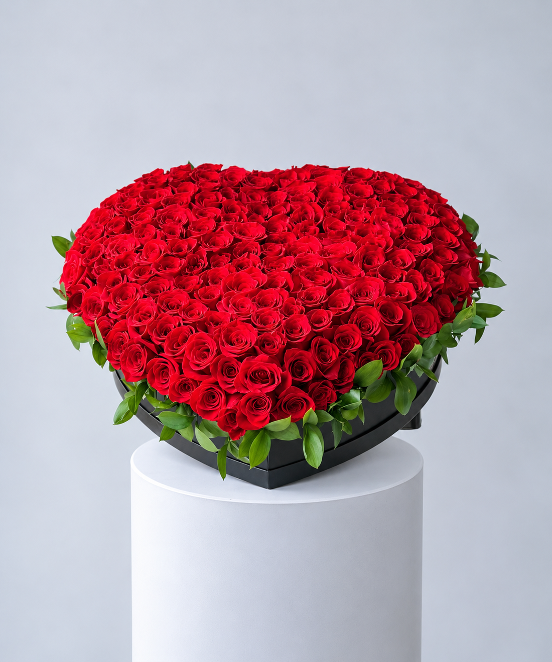 luxury heart-shaped red rose arrangement featuring hundreds of fresh red roses with lush green foliage, presented in a black heart-shaped box for romantic gifting in Abu Dhabi and Dubai