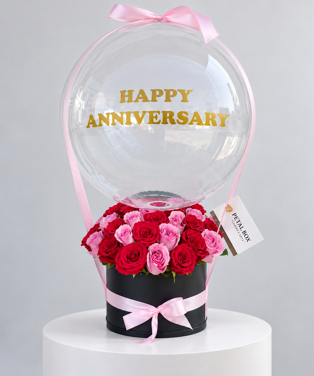 luxury anniversary rose arrangement featuring red and pink roses in a black Petal Box, topped with a clear balloon and pink ribbon, personalised with “Happy Anniversary” for elegant gifting in Abu Dhabi and Dubai