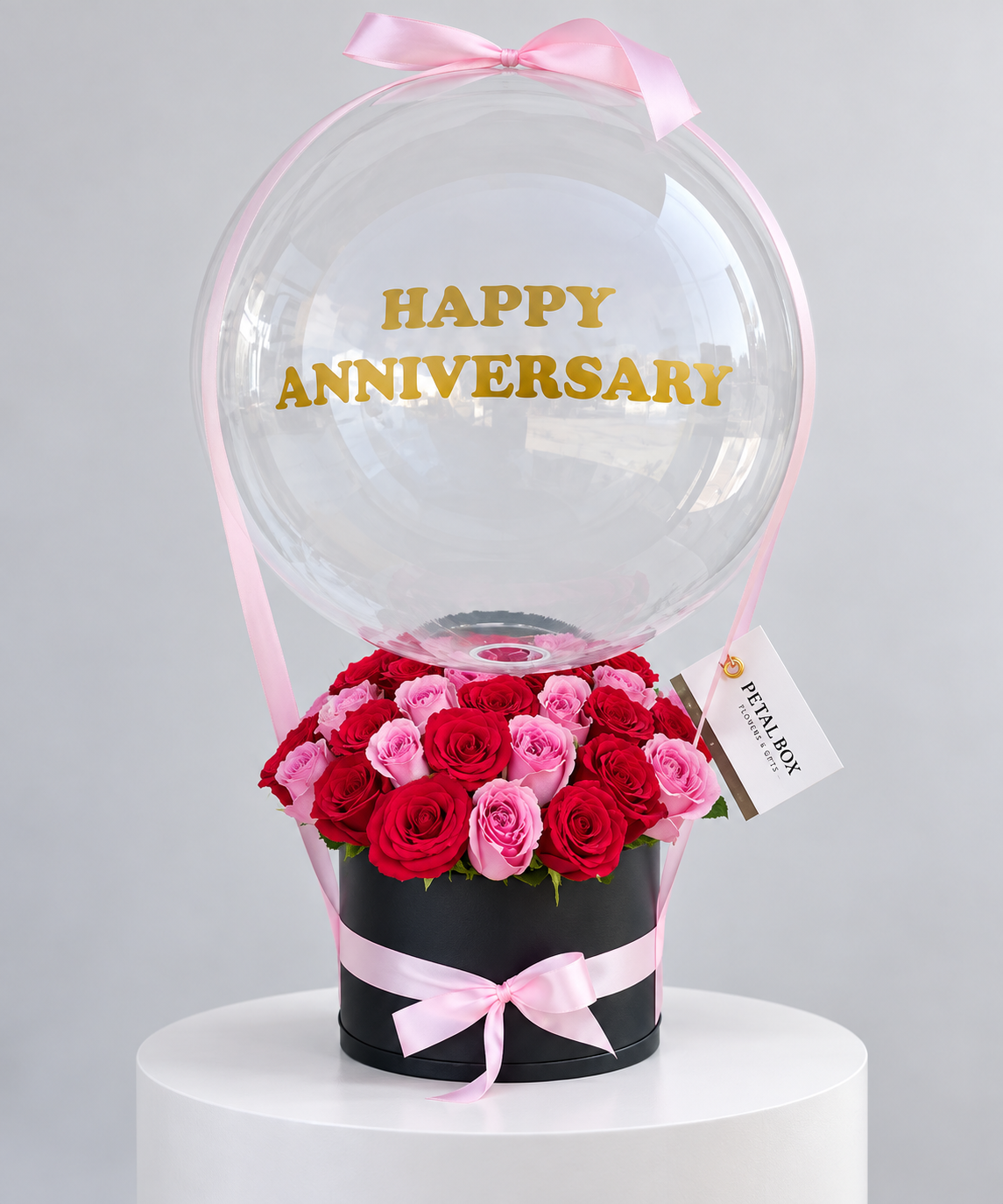 luxury anniversary rose arrangement featuring red and pink roses in a black Petal Box, topped with a clear balloon and pink ribbon, personalised with “Happy Anniversary” for elegant gifting in Abu Dhabi and Dubai