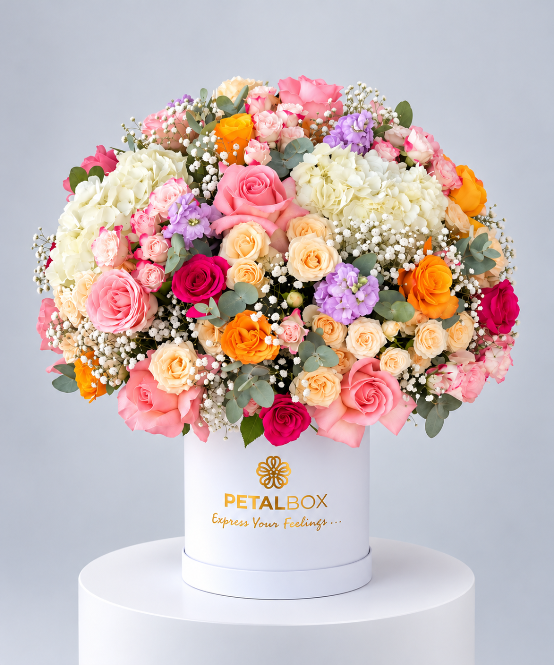 luxury multicolor flower bouquet in a white Petal Box hatbox featuring pink, peach, yellow, orange, cream and purple roses with white hydrangeas, baby’s breath and eucalyptus, elegant floral arrangement for gifting in Abu Dhabi and Dubai