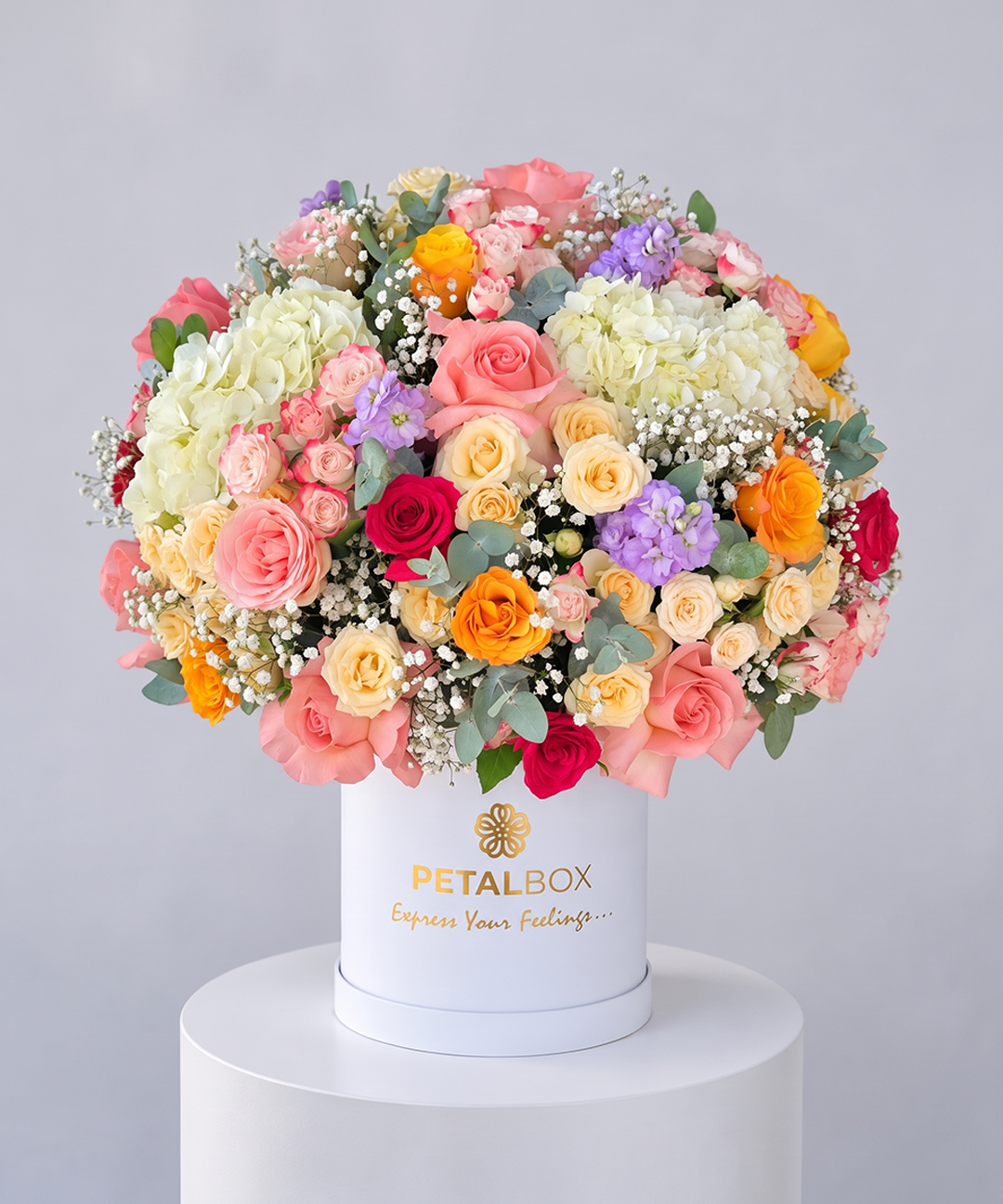 luxury multicolor flower bouquet in a white Petal Box hatbox featuring pink, peach, yellow, orange, cream and purple roses with white hydrangeas, baby’s breath and eucalyptus, elegant floral arrangement for gifting in Abu Dhabi and Dubai