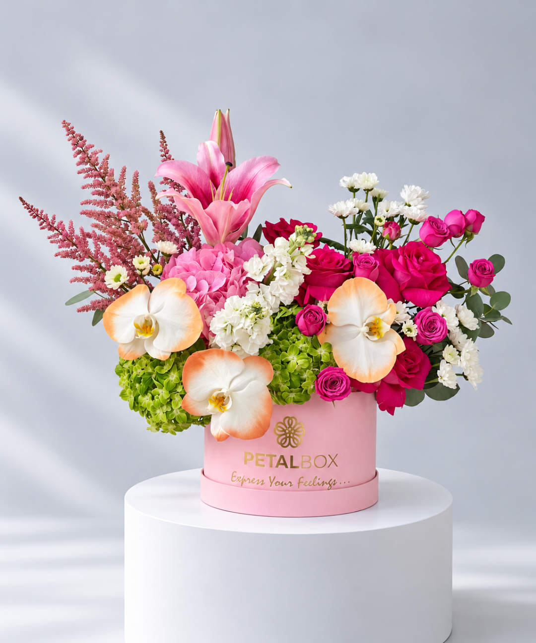 Pink lily, orchids and hydrangea in a round pink velvet hatbox