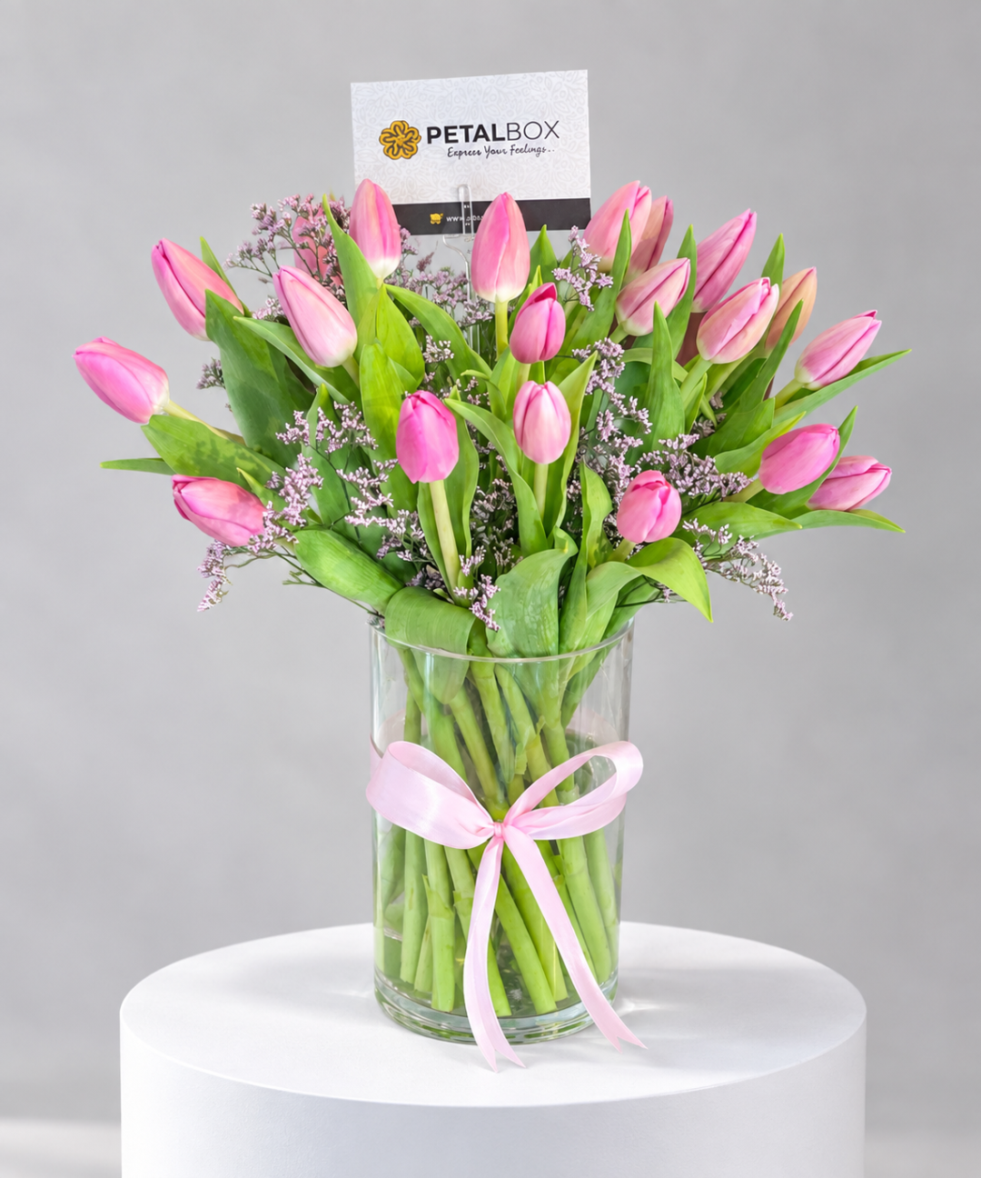 luxury pink tulip bouquet featuring fresh pink tulips, delicate purple filler flowers and lush green foliage, arranged in a clear glass vase with a pink satin ribbon by Petal Box, elegant flower delivery in Abu Dhabi and Dubai for birthdays, anniversaries and special occasions