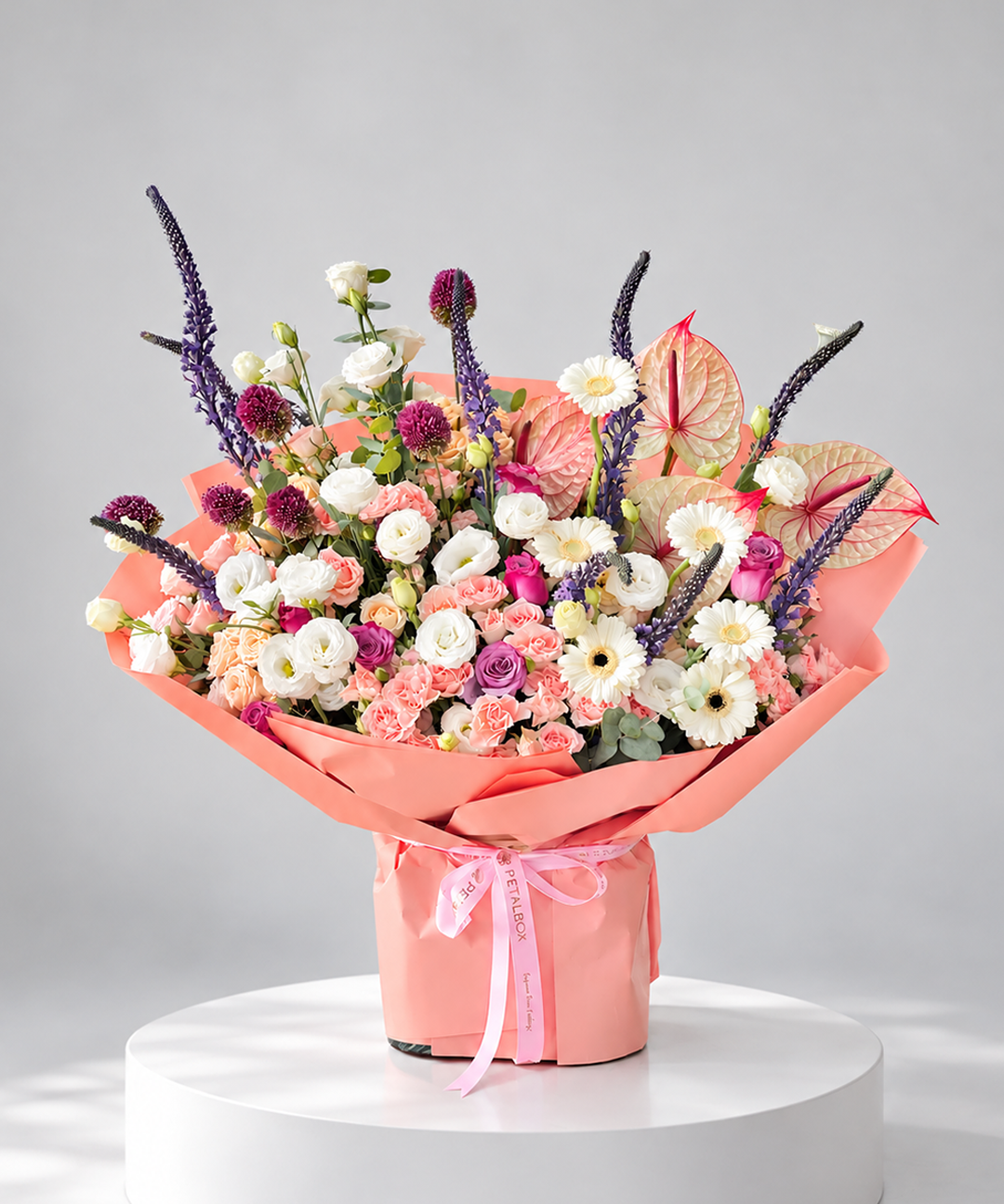 luxury mixed flower bouquet in pink wrapping with white roses, peach carnations, purple veronica, anthuriums, daisies and delicate foliage, elegant Petal Box floral arrangement for gifting in Abu Dhabi and Dubai