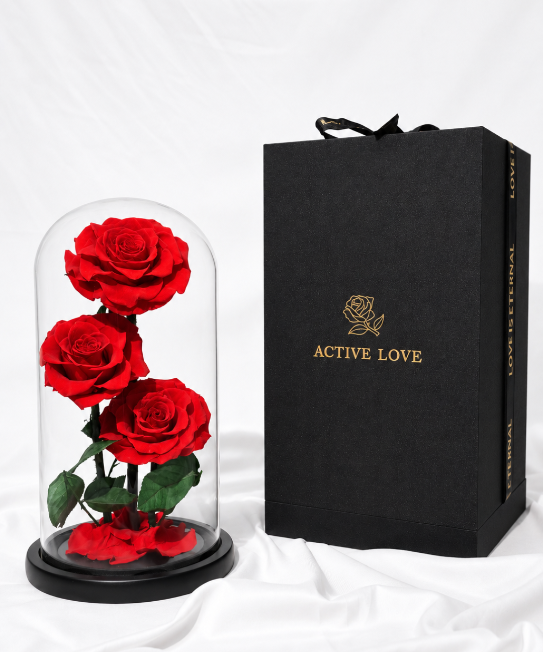 Luxury triplet red forever roses preserved under a glass dome with a premium black Active Love gift box featuring elegant gold branding, an everlasting rose gift for anniversaries, romantic occasions and Valentine's Day, available with flower gifting delivery in Abu Dhabi and Dubai, UAE.