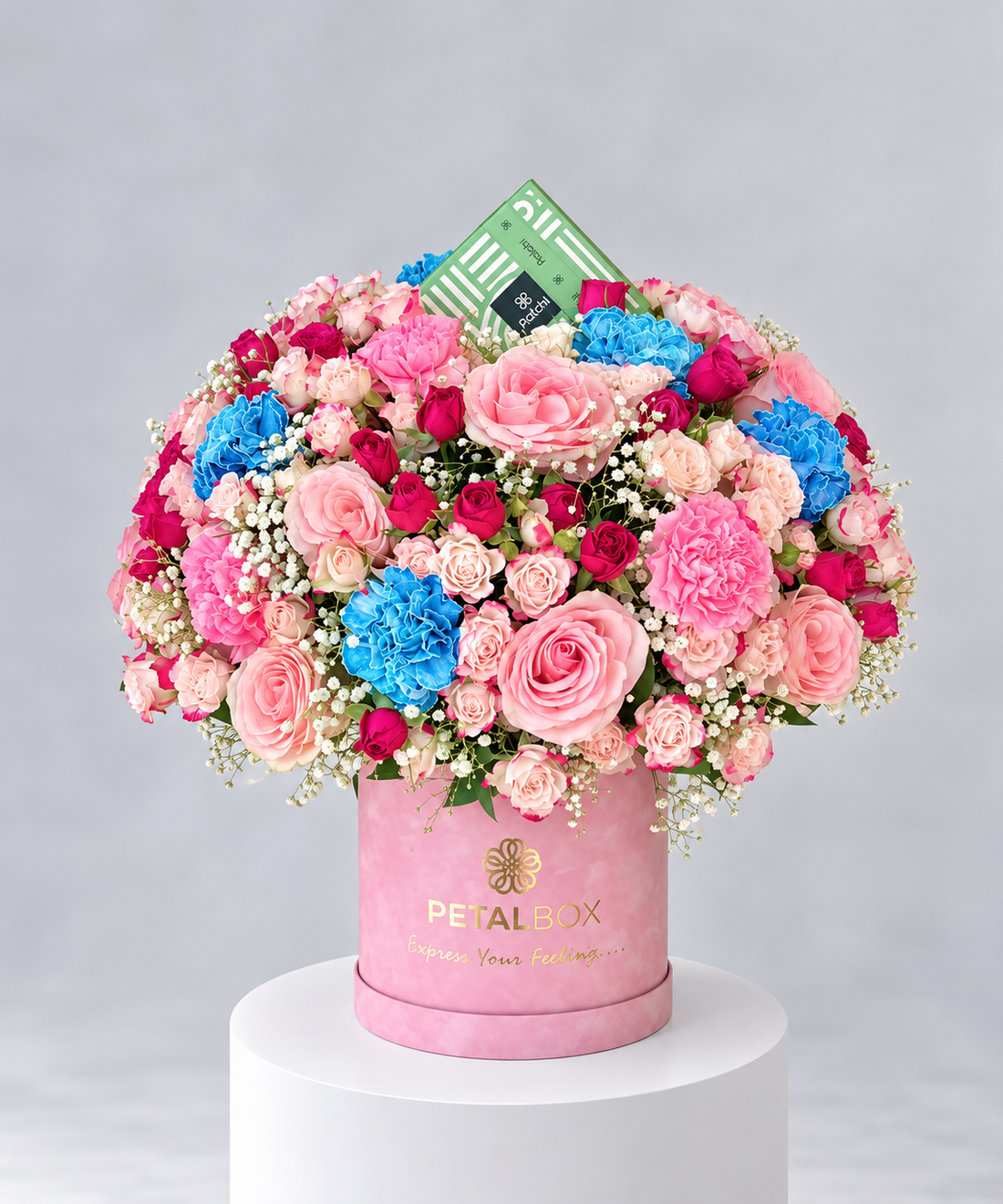luxury pastel flower bouquet in a pink Petal Box hatbox featuring pink roses, mini roses, carnations, bright blue flowers and baby’s breath, elegant floral arrangement for gifting in Abu Dhabi and Dubai