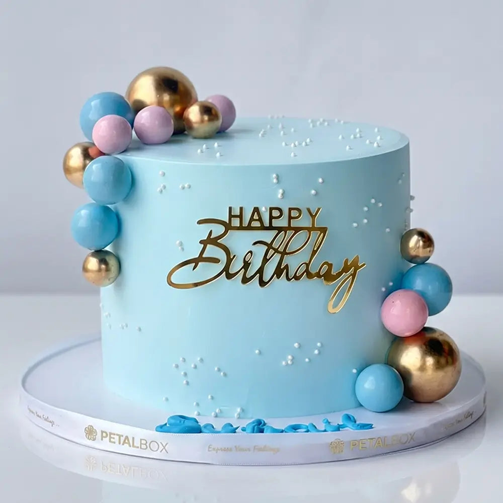 Blue birthday cake with gold, pink and blue decorative ball clusters and gold Happy Birthday topper, Petal Box Abu Dhabi