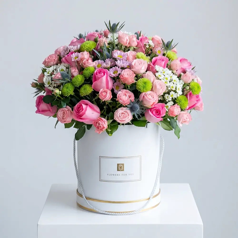 Elegant pink mixed flower arrangement with pink roses, spray roses, chrysanthemums, green button flowers, and fresh greenery in a luxury white floral box for premium gifting in Abu Dhabi and Dubai.