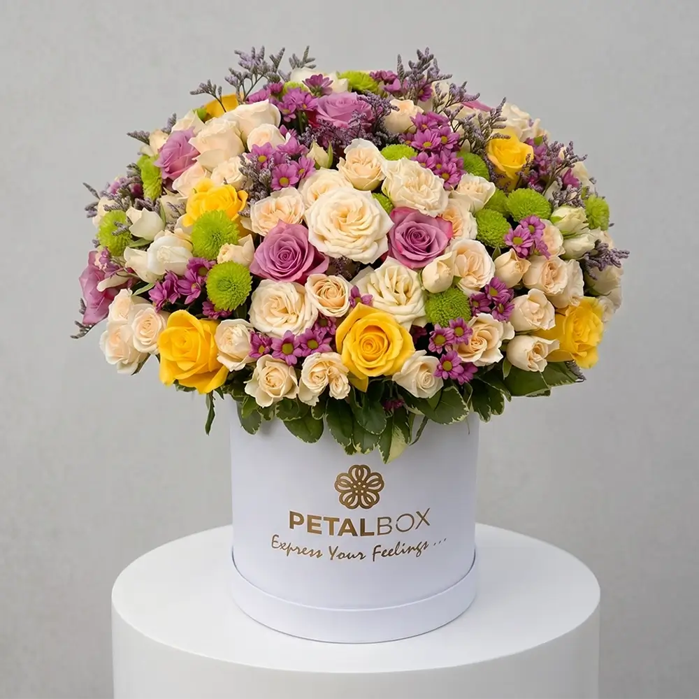 luxury mixed flower box with yellow roses, lavender roses, white spray roses and purple chrysanthemums in an elegant white hat box, premium floral arrangement by Petal Box UAE for flower delivery in Abu Dhabi and Dubai