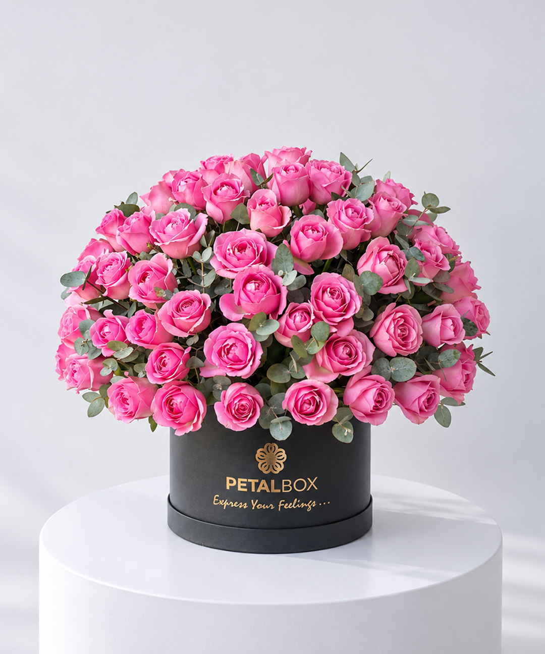 luxury pink rose bouquet arranged in a black Petal Box hatbox with eucalyptus foliage, premium flower arrangement on a white pedestal for gifting in Abu Dhabi and Dubai