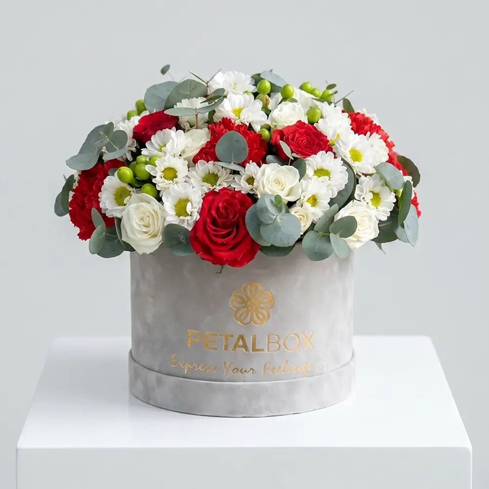 Elegant red and white flower box arrangement with red roses, white daisies, white spray roses, eucalyptus, and fresh greenery in a luxury Petal Box display.