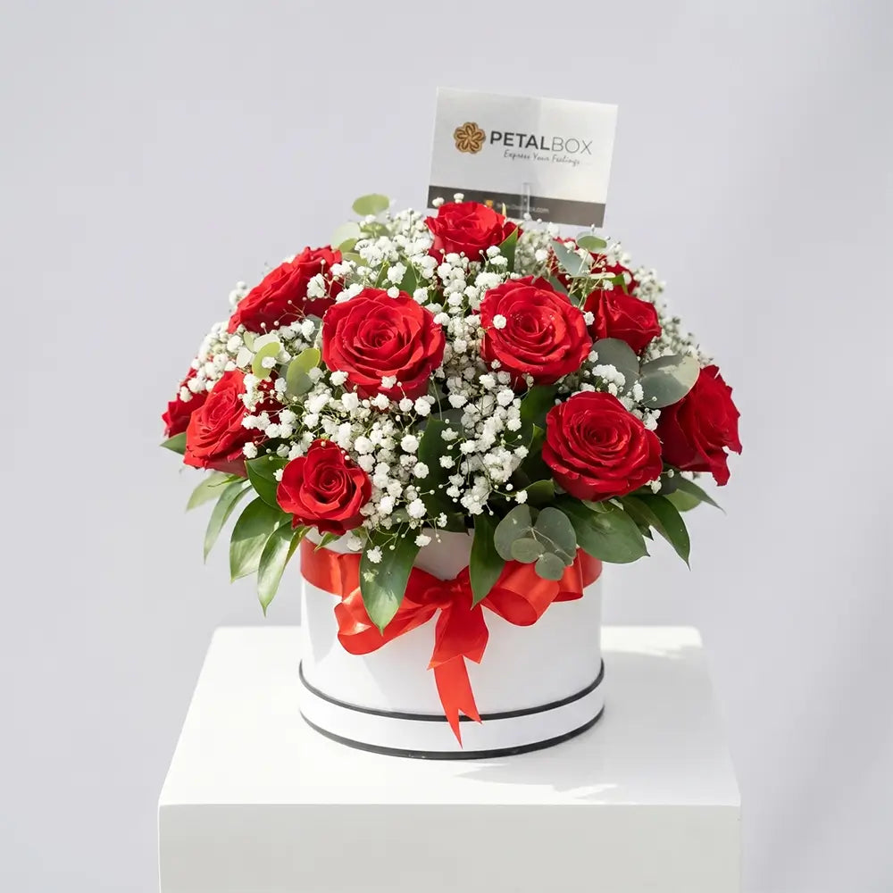 Elegant red rose arrangement with baby’s breath and eucalyptus in a white hat box with red ribbon, styled as a luxury floral gift by Petal Box.