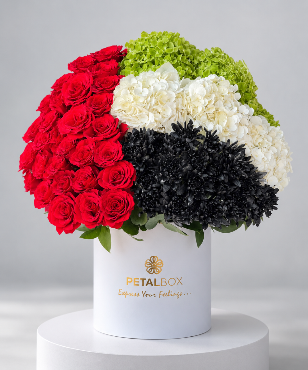 White round box with the UAE flag made of red roses, hydrangea and black chrysanthemums