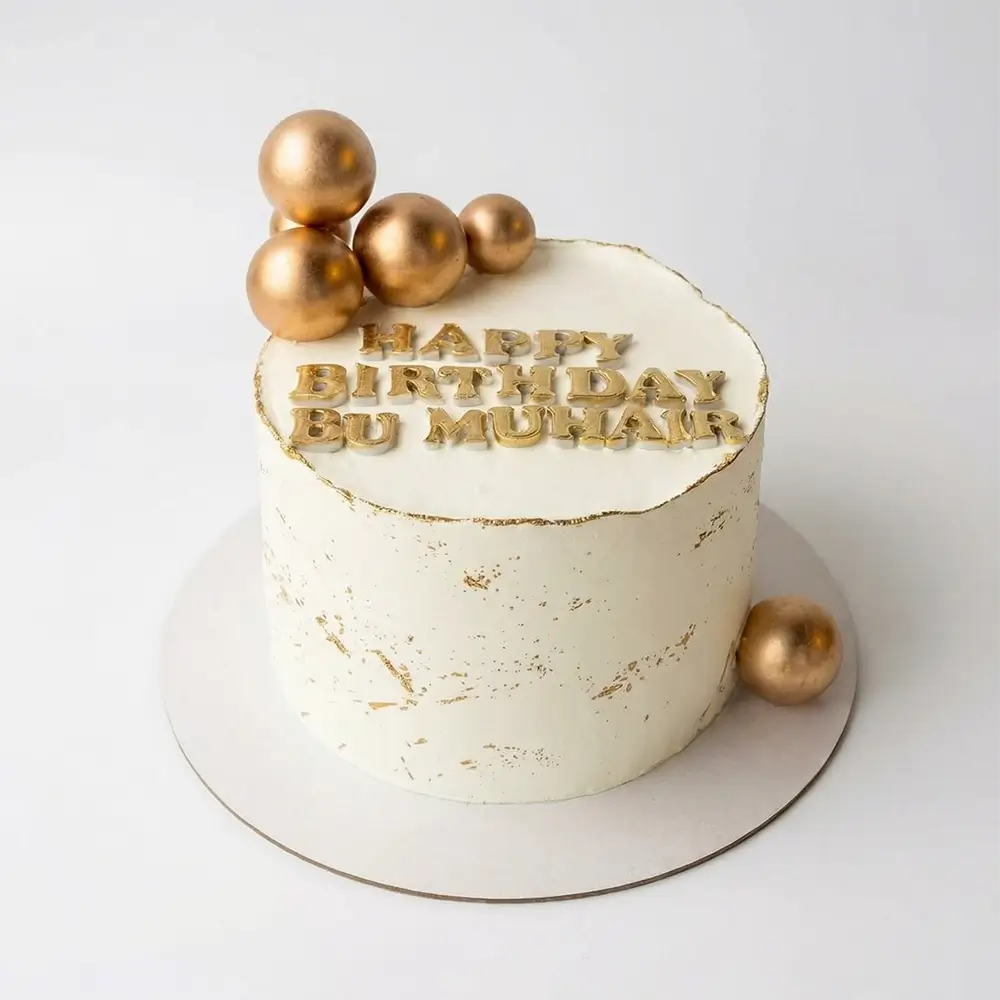 White and gold birthday cake with gold leaf splatter texture, chrome gold ball cluster and personalised gold letter name topper