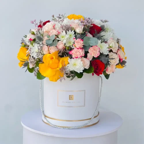 luxury mixed flower box with yellow and red roses, spray roses, white chrysanthemums and eucalyptus in an elegant white hat box, premium floral arrangement for flower delivery in Abu Dhabi and Dubai UAE