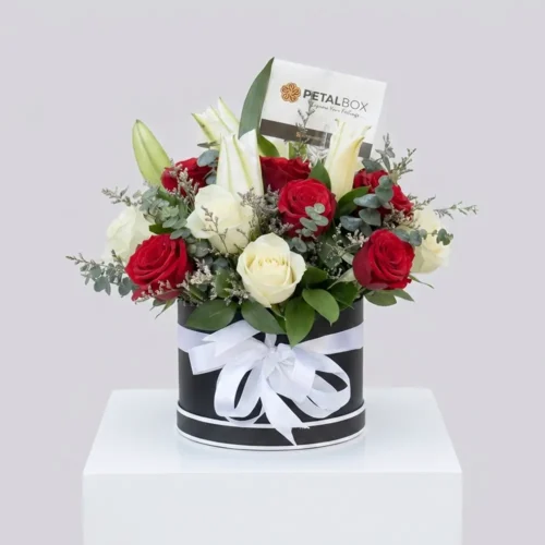 Luxury red and white rose arrangement with white lilies and eucalyptus in a black floral box with white ribbon by Petal Box.