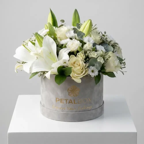 Elegant white lily and rose flower box arrangement with white chrysanthemums, eucalyptus, and fresh greenery in a luxury Petal Box floral display.