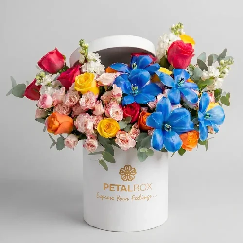 colorful mixed flower box with blue lilies, roses and spray roses, luxury floral arrangement in white hat box by Petal Box UAE, premium flower delivery in Abu Dhabi and Dubai