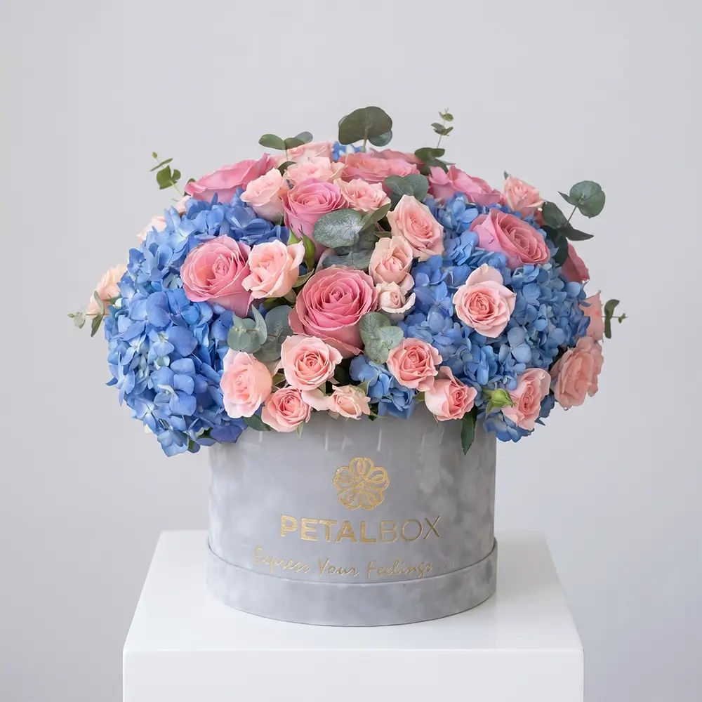 Luxury blue hydrangea and pink rose flower box arrangement with blush spray roses and eucalyptus in a premium velvet Petal Box, styled for elegant gifting and special occasions.