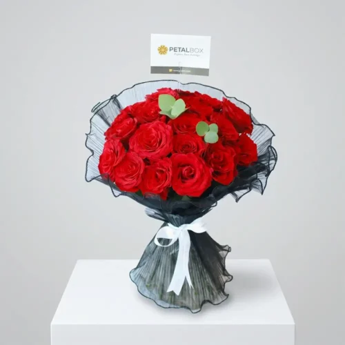 Luxury red rose bouquet with elegant black mesh wrapping, white ribbon, and fresh red roses styled for premium romantic gifting by Petal Box.