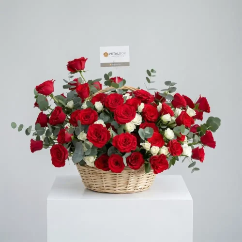 Luxury red and white rose basket arrangement featuring premium fresh red roses, delicate white spray roses, and fresh eucalyptus styled in a classic woven basket with an elegant balanced floral composition.