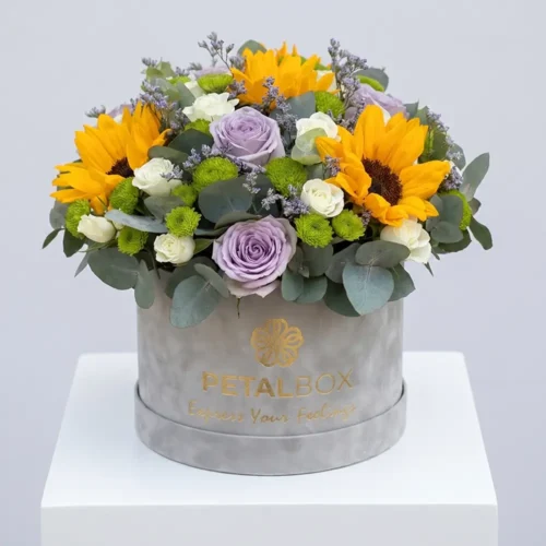Elegant sunflower and lavender rose flower box arrangement with white spray roses, green chrysanthemums, and eucalyptus in a luxury Petal Box display.