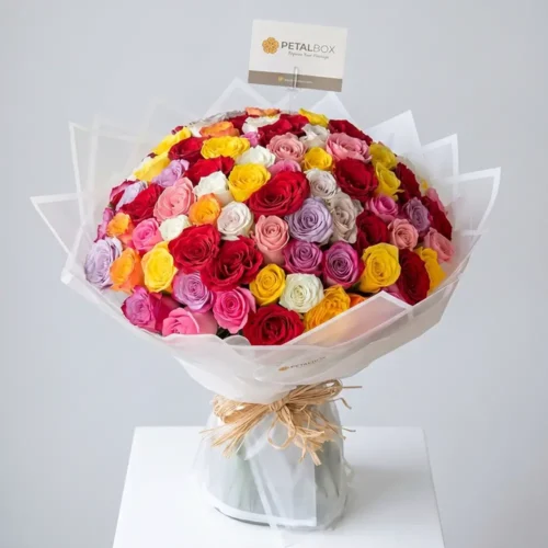 Luxury 100 mixed rose bouquet with red, pink, yellow, white, peach, and lavender roses in elegant premium wrapping, designed for grand gifting and special occasions by Petal Box Dubai.