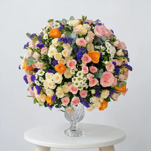 Mixed rose glass vase arrangement with pink roses, orange roses, white Santini and purple Statice for flower delivery in abu dhabi & Flower Delivery in Dubai