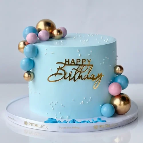 Blue birthday cake with gold, pink and blue decorative ball clusters and gold Happy Birthday topper, Petal Box Abu Dhabi