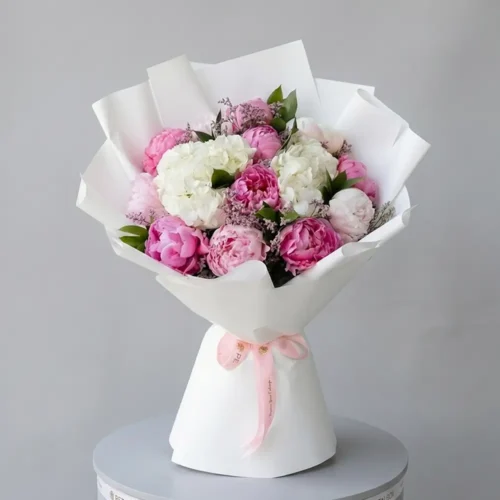 Pink peony and white hydrangea bouquet wrapped in white matte paper with pink satin ribbon by Petal Box, available for same-day flower delivery in Dubai and Abu Dhabi