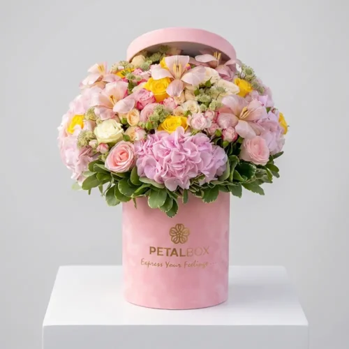 Luxury pastel flower arrangement with pink hydrangeas, blush roses, yellow roses, orchids, and fresh greenery in an elegant pink Petal Box for premium gifting in Abu Dhabi and Dubai.